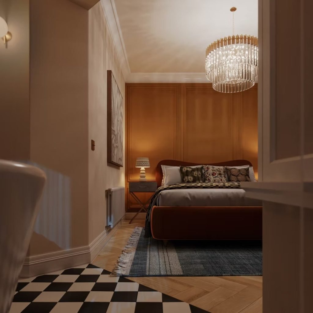 Bedroom with a rust velvet bed, a burnt-orange panelled wall, a glass chandelier and a checkerboard tiled floor.