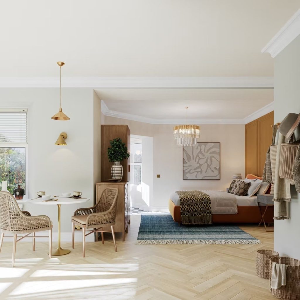 Open-plan suite pairing a dining nook with a rust velvet bed beneath a glass chandelier, framed by soft sage walls.