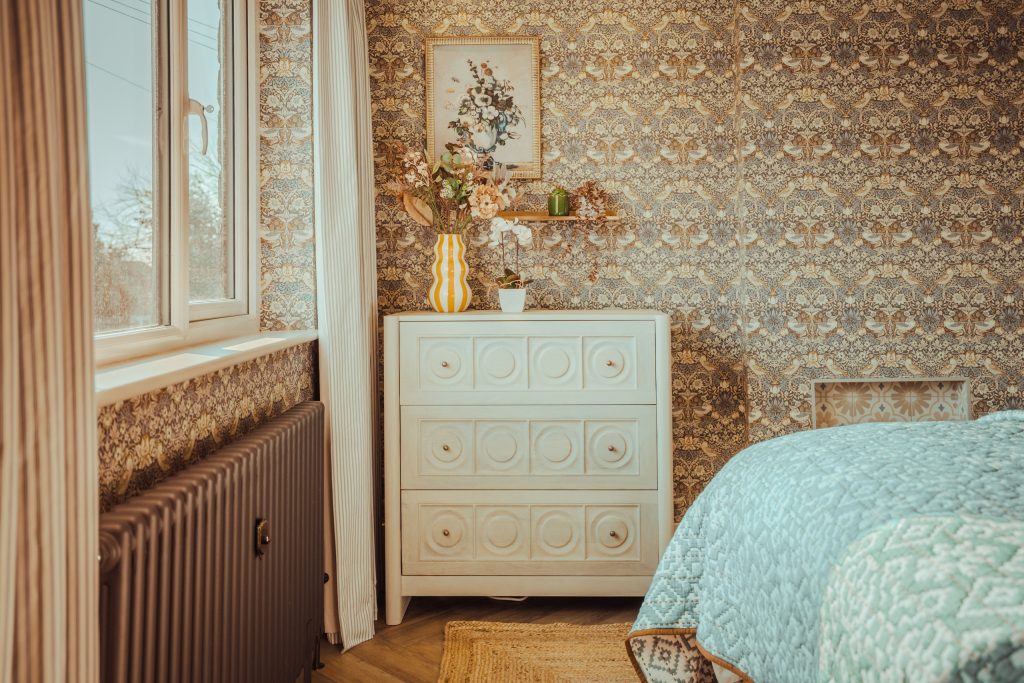 Discover this cozy serviced accommodation in Beckwithshaw, North Yorkshire, featuring an inviting bedroom corner with intricate floral-patterned wallpaper, a white vintage dresser...