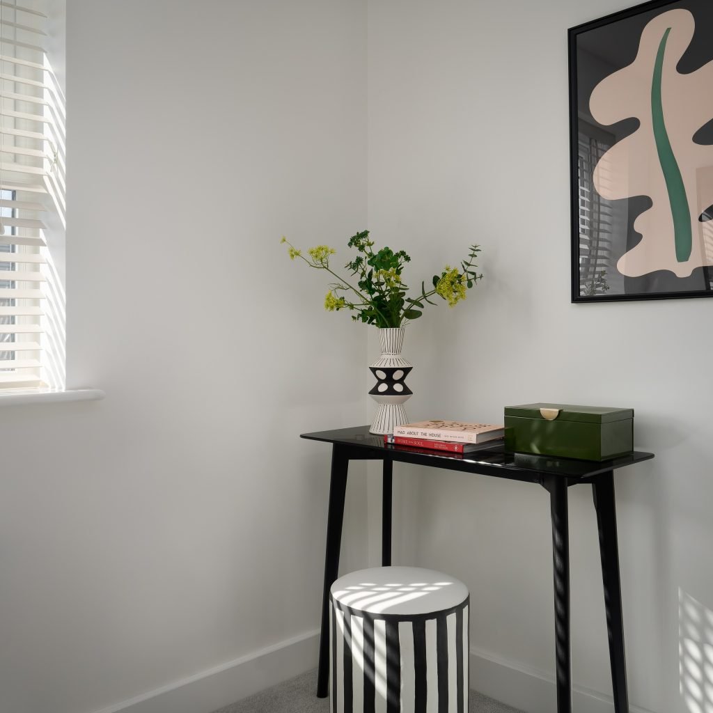 Explore this elegant study nook in the Foxes Chase home, East Riding Yorkshire, featuring a sleek black writing desk, striped stool, contemporary vase with green and yellow blooms...
