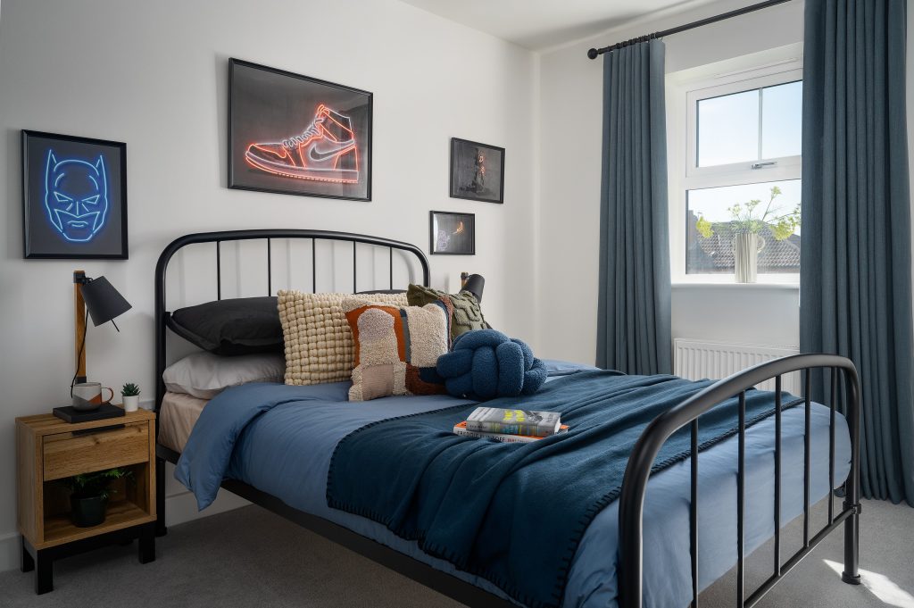 Discover the contemporary elegance of the Foxes Chase home bedroom in East Riding Yorkshire, featuring a sleek black metal bed frame, layered blue bedding, textured accent pillows...