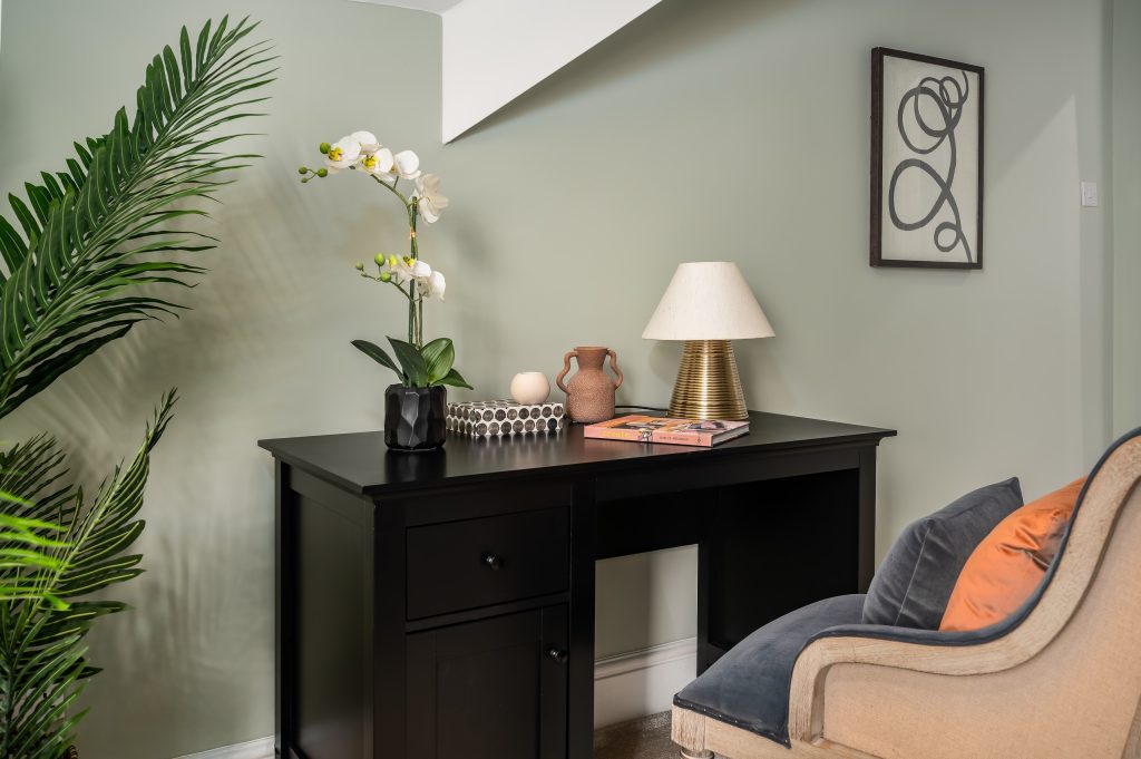 Study nook with a black writing desk, table lamp and an adjacent armchair.