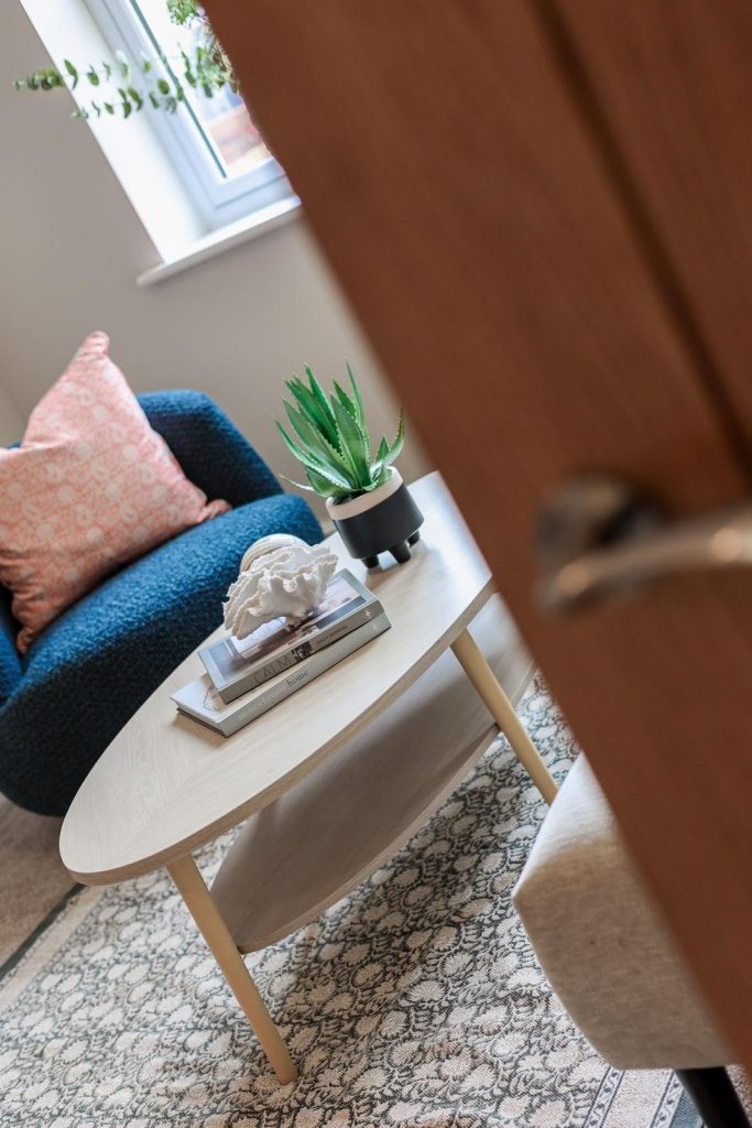 A cosy seating nook in a Huntingdon, York home staged by WildKind Interiors. The vignette features a light wood oval coffee table with a decorative coral sculpture, coffee-table books...