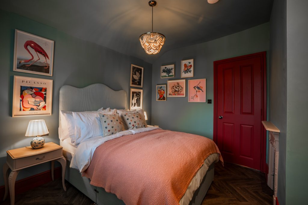 A vibrant upstairs bedroom in Magazine Lane serviced accommodation, The Wirral, styled by WildKind Interiors. This room features a plush upholstered bed dressed in crisp white linens...