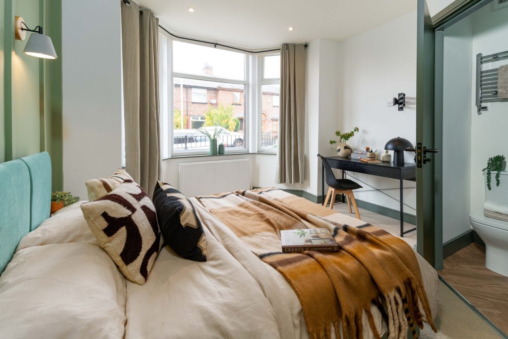 Tenant bedroom with a teal headboard, a bay window and a private en-suite beyond.