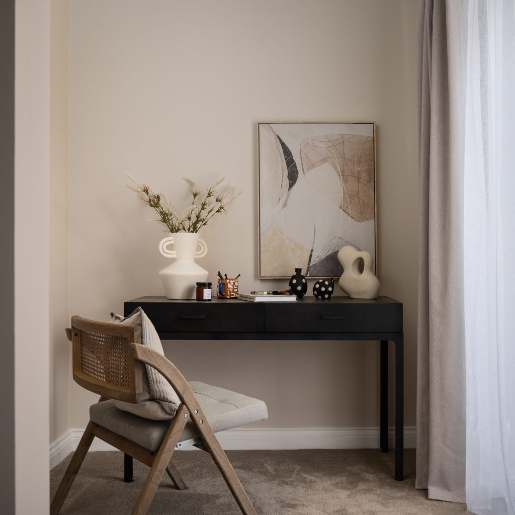 Study nook with a black writing desk, sculptural decor and abstract wall art.