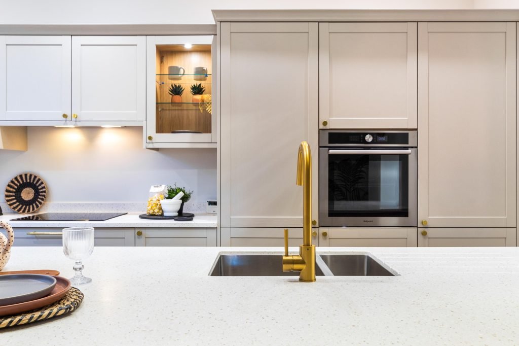 This beautifully staged Scartho kitchen features a central island topped with a crisp, speckled quartz countertop, accentuated by a sleek gold-finish mixer tap and a stainless-steel double...