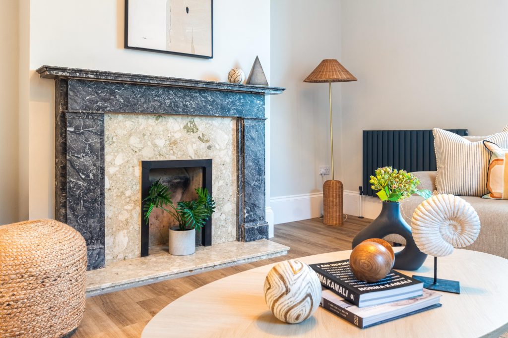 This elegantly staged living area in Scartho, Lincolnshire features a luxurious black-and-white marble fireplace with a contrasting pale stone hearth. A woven jute pouffe sits beside...