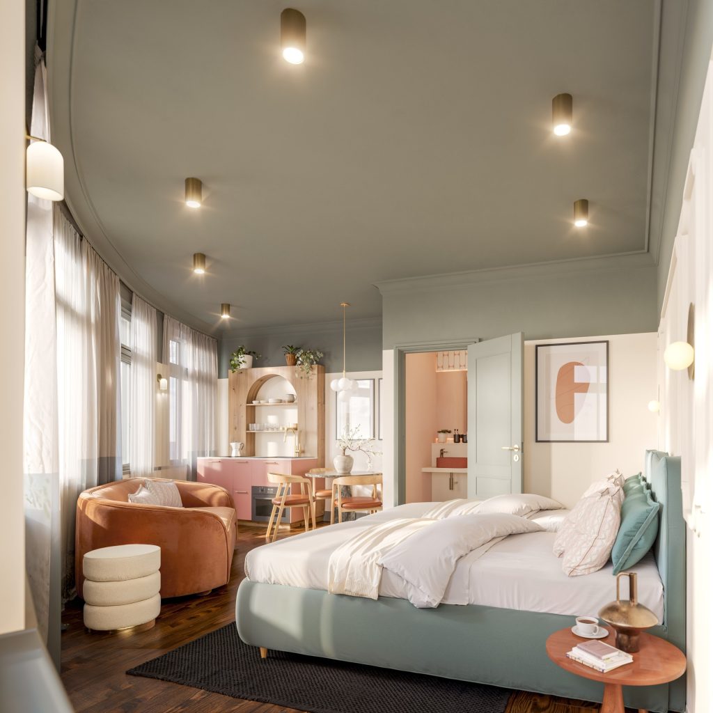 Studio suite pairing a bed with a coral-toned lounge area, statement pendant lighting and framed art.