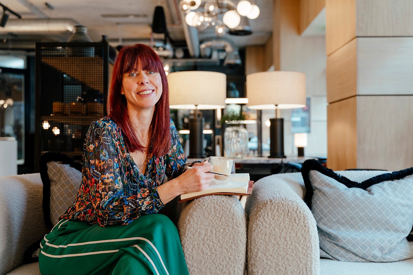 Louise sat on a sofa with a notepad and coffee